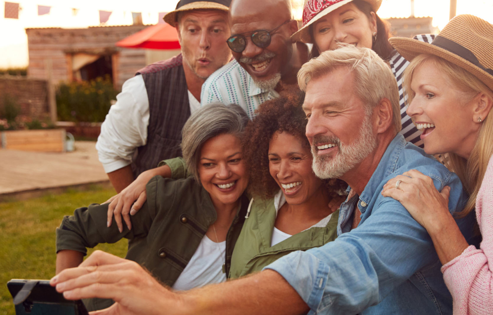 Group of people smiling and taking a selfie together outside.